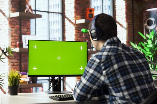 Home office worker using mockup computer, engaging in call, participating in virtual meeting with colleagues. Man discussing with coworkers during videoconference meeting on green screen PC photo