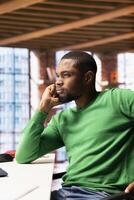 Man having hard time coming up with ideas for work project at home office desk. Stumped african american remote employee ruminating in apartment workspace, thinking how to solve tasks photo