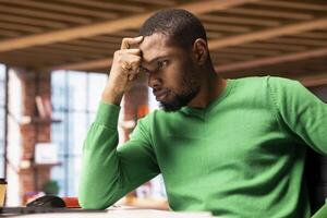 Frustrated remote worker at home office desk browsing internet on notebook feeling bored while researching information online. Annoyed student tired of reading articles for school tasks photo