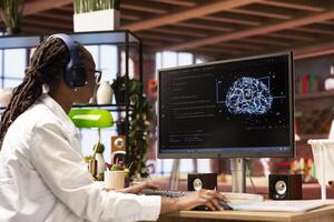 Programmer wearing headphones using computer at home for artificial intelligence computing simulating human brain. IT professional listening music and working with AI deep neural networks at home photo