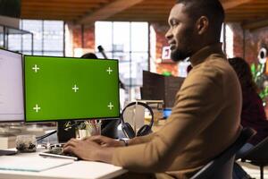 Programmer coding in AI startup office using mockup PC, building scalable solutions for businesses. AI industry startup technician leveraging machine learning technology on green screen computer photo
