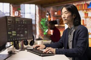 Senior technician coding advanced AI algorithm in startup office, refining machine learning models to enhance automation. Asian CTO manager using coding platform in Silicon Valley workplace photo