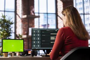 Mature woman engaging with AI chatbot on pc next to isolated display, using the virtual assistant with prompts for data driven algorithms to enhance productivity at home office. photo