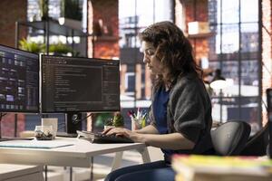 African american software engineer works on dual monitors and typing code for a development project. Technical developer multitasking, debugging and using advanced digital tools for coding. photo