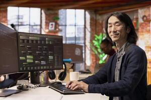 Portrait of happy CTO manager using PC in startup office to design and implementing algorithms enabling machine learning. Cheerful tech venture senior technician conducts code reviews to fix bugs photo