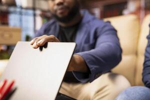 Black man prioritizes self care and mental wellbeing for his wife by closing the laptop and urging for a break. Supportive conversation helps them recharge and reduce stress in living room. Close up. photo