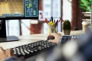 Freelancing architectural designer in home office operating 3D modeling application, importing furniture elements from library, placing them on floor. Close up of man making floor plan in CAD software photo