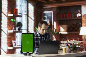 Employee seated at home office desk uses chroma key device, checking emails displayed on screen, reading messages in inbox. Close up of man managing electronic correspondence on isolated screen tablet photo