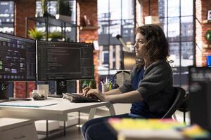 Software developer at agency office coding on her computer creating a software and works on implementing algorithms. IT expert building applications with a programming interface. photo