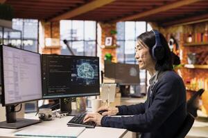 Senior programmer coding advanced AI algorithm in startup office, refining machine learning models to enhance automation, wearing headphones. Asian CTO manager listening music and coding photo