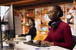 Silicon Valley venture engineer solving tasks with AI LLM chatbot answering prompts using predictive technology. African american startup IT worker using computer to interact with generative model app photo