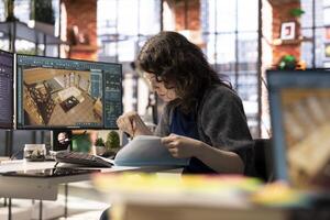 Graphic artist uses architectural software on her PC to create a detailed 3D render of a home interior. The program allows to configure furniture and other design elements for a virtual layout. photo