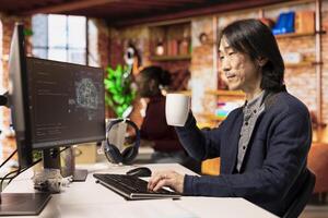 Senior programmer in artificial intelligence focused startup drinking coffee, coding and debugging applications. Experienced IT professional doing code testing and quality assurance, enjoying beverage photo