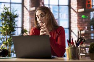 Adult joining online lesson to work on new skills from home office, attend web conference call and watching lecture from her apartment. Woman participates at a virtual training class. photo
