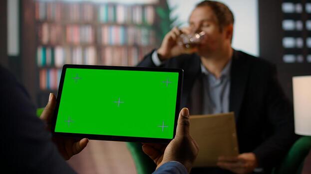 Diverse secret agents examine clues at CIA secret base with a green screen, working on surveillance systems and collecting data to help on mission. Drinking whiskey at the classy library. Camera A. photo