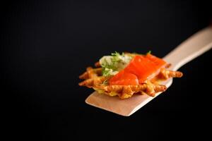 Quick snack.vegetable potato waffles with spread and lightly salted red fish on a spatula photo