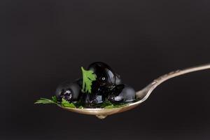 Black shiny olives in a spoon. photo