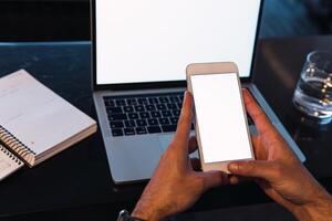 Anonymous man browsing smartphone with laptop on photo