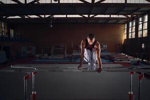 Young male gymnast doing exercises on the parallel apparatus. photo