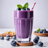 Glass of blueberry smoothie with fresh berries on light background. Close-up food image for use in product design photo