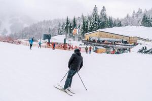 Skier rides, leaning sideways, along a snowy slope at the Kolasin 1600 ski resort. Montenegro. Back view photo