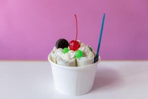 Close up of a rolled ice cream decorated with a cherry, a cookie and green bubble toppings photo