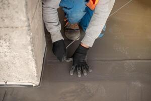 Worker working on the floor of an industrial building. Construction worker producing grout and finishing wet concrete floor. photo