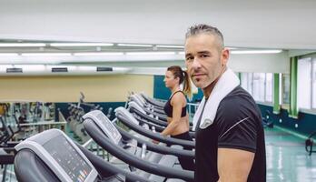 Man with towel in neck training over treadmill photo