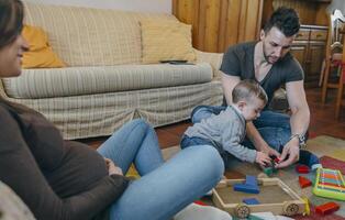 Father playing with toddler while the mother is looking at them photo