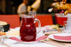 Decanter of berry juice stands on a laid table in a restaurant photo