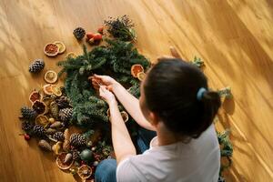 Designer ties a frame of a Christmas wreath of spruce branches with a string. Top view photo