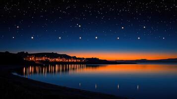Night sky over coastal town with lights reflecting on calm water. photo