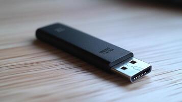 Sleek black USB drive on wooden surface. photo