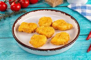 A bowl of fried chicken on a table with tomatoes and spices photo