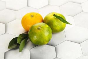 Three oranges and a lime on a white surface photo