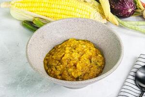 A bowl of corn soup next to a bowl of corn on the cob photo