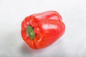 A red pepper is shown on a white surface photo