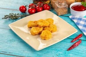 Fried chicken nuggets on a white plate on a blue table photo