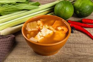 A bowl of soup with a bowl of vegetables and a knife photo