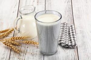 A glass of milk next to wheat and a jug photo