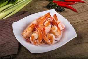 A white plate with shrimp and vegetables on a wooden table photo