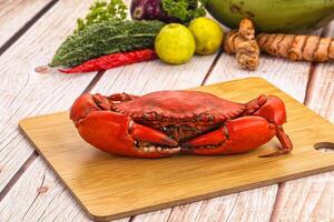 A crab on a cutting board with vegetables and other food photo