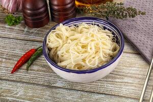 A bowl of noodles and chopsticks on a wooden table photo
