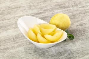 A bowl of sliced yellow peaches on a table photo