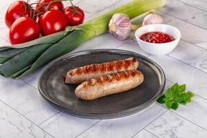 Two sausages on a plate with tomatoes and other ingredients photo