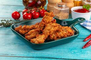 A plate of fried chicken with a bottle of ketchup and a bottle of ketchup photo
