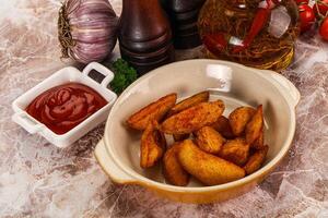 A bowl of potato chips and a bottle of ketchup photo