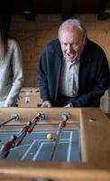 A granddaugther and his grandfather are playing table football game together photo