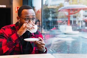Black man with cup of coffee in cafe photo