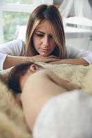 Baby sleeping on a blanket while her mother looks photo